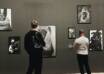 Visitors viewing black-and-white portrait photography in a contemporary gallery space during an Art Exhibition Lahore, with framed artworks displayed on dark walls.